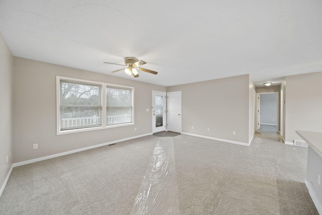 empty room with light carpet, ceiling fan, visible vents, and baseboards