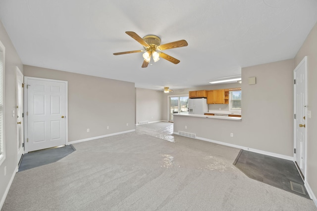 unfurnished living room featuring carpet flooring, visible vents, ceiling fan, and baseboards