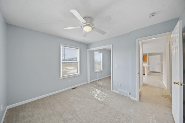 unfurnished bedroom with light carpet, baseboards, visible vents, and a ceiling fan