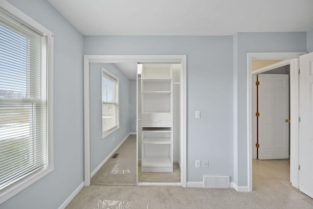 unfurnished bedroom with light carpet, a closet, visible vents, and baseboards