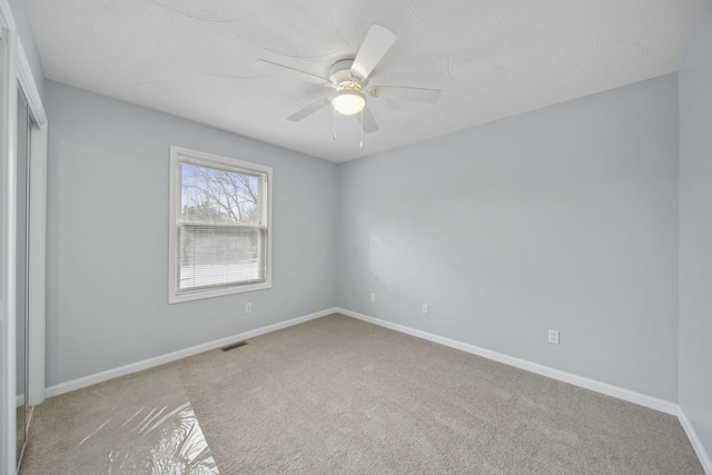 unfurnished bedroom featuring a ceiling fan, light colored carpet, visible vents, and baseboards