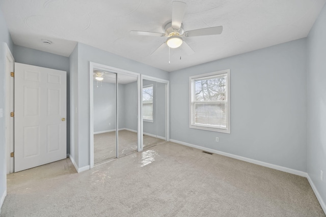 unfurnished bedroom with a ceiling fan, light colored carpet, visible vents, and baseboards