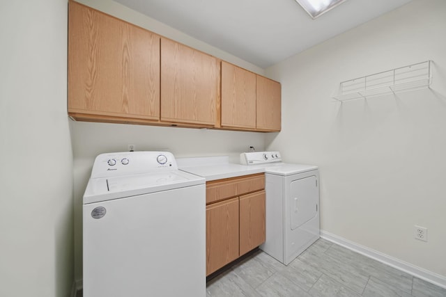 washroom with cabinet space, baseboards, and independent washer and dryer