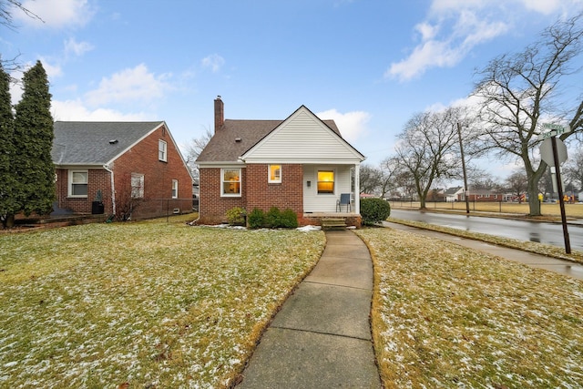 view of front of property with brick siding, fence, a chimney, and a front lawn