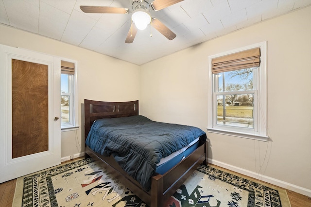 bedroom featuring ceiling fan, baseboards, and wood finished floors