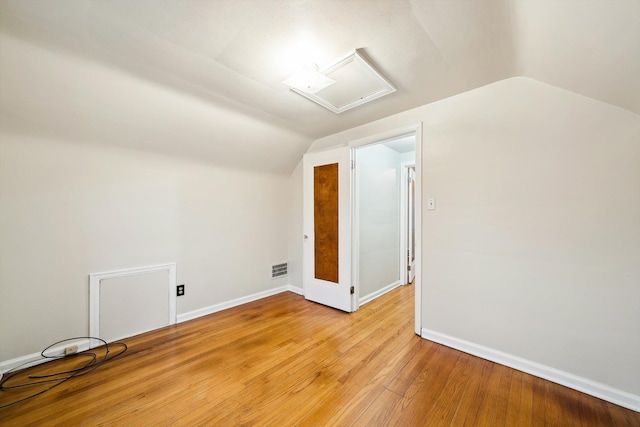 additional living space featuring attic access, light wood-type flooring, lofted ceiling, and baseboards