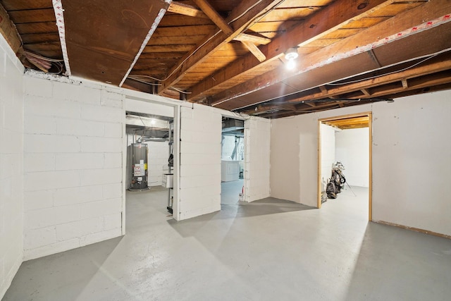 unfinished below grade area with washing machine and dryer, gas water heater, and concrete block wall