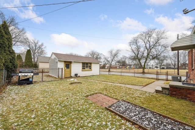 view of yard featuring an outbuilding, central AC unit, fence, and a gate