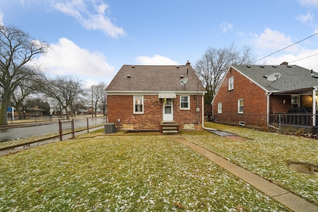 rear view of house with brick siding, a lawn, entry steps, fence, and cooling unit