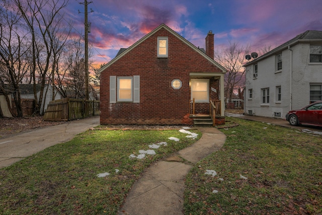 bungalow-style house featuring brick siding, a yard, a chimney, and fence