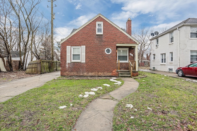 bungalow-style home featuring brick siding, a chimney, a front lawn, and fence