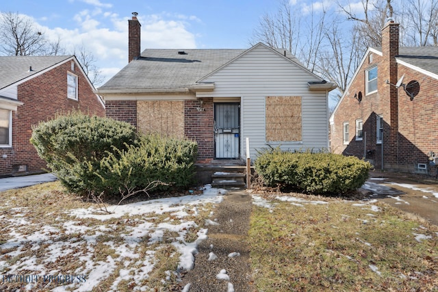 bungalow-style house with brick siding and a chimney