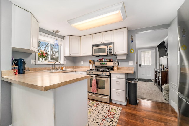 kitchen featuring a peninsula, stainless steel gas range oven, a sink, and a healthy amount of sunlight