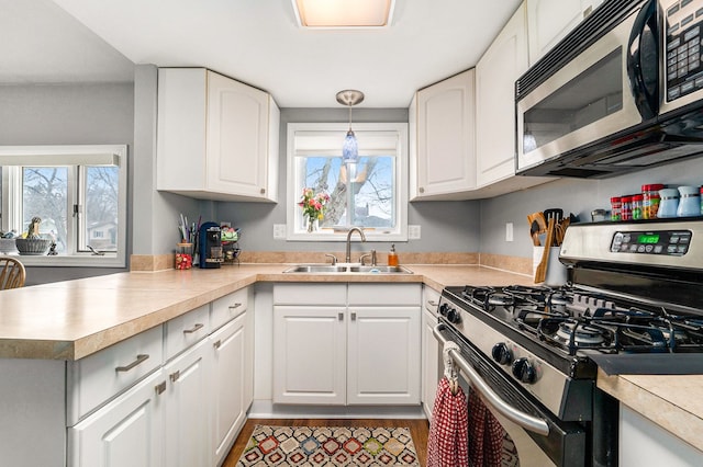 kitchen with a peninsula, stainless steel appliances, a sink, and light countertops