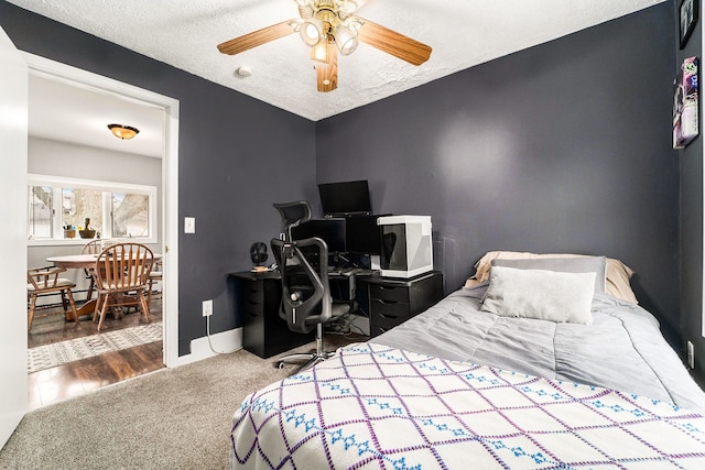 carpeted bedroom with ceiling fan, baseboards, and a textured ceiling