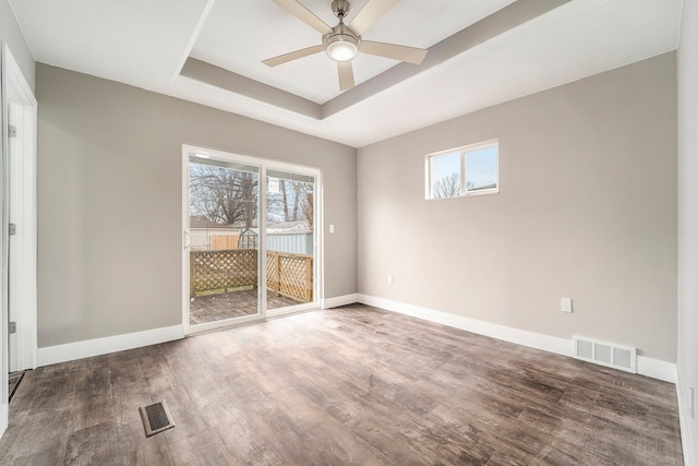 empty room with a raised ceiling, visible vents, and plenty of natural light