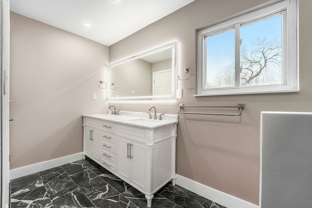 full bathroom with marble finish floor, a sink, baseboards, and double vanity