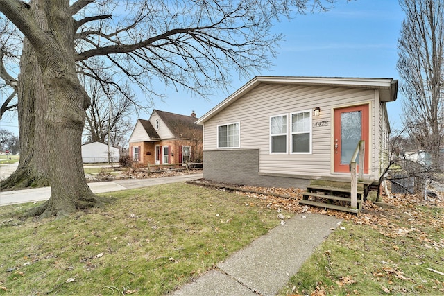 bungalow-style home with a front yard, brick siding, and entry steps