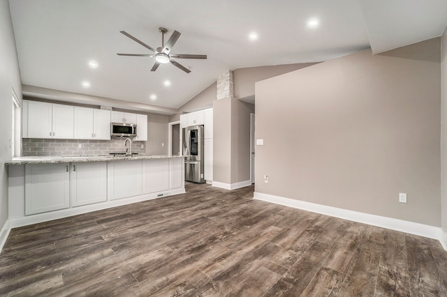 kitchen with light stone counters, dark wood-style flooring, a peninsula, stainless steel appliances, and white cabinetry