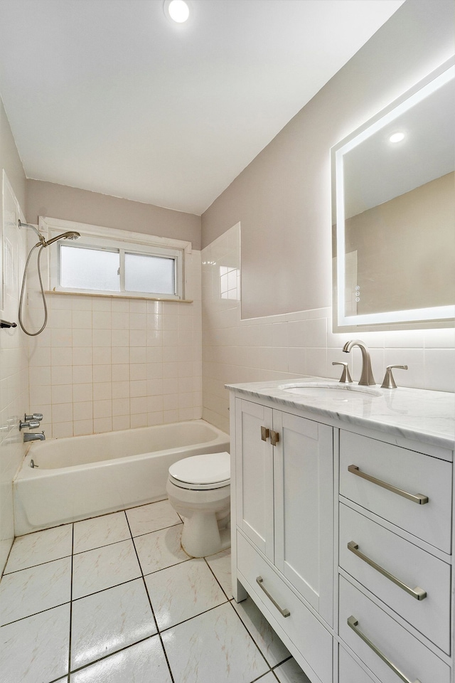 full bathroom featuring toilet, bathing tub / shower combination, vanity, and tile walls