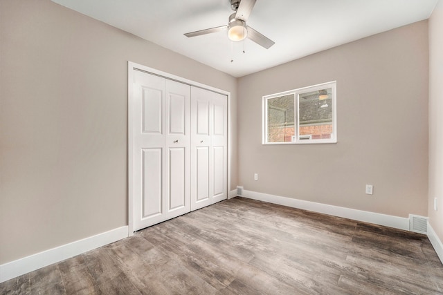 unfurnished bedroom featuring a closet, wood finished floors, visible vents, and baseboards