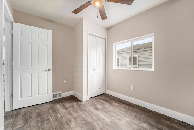 unfurnished bedroom featuring a closet, visible vents, a ceiling fan, wood finished floors, and baseboards