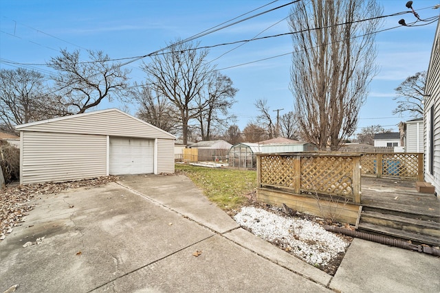 view of yard featuring an outbuilding, a detached garage, an exterior structure, a deck, and driveway