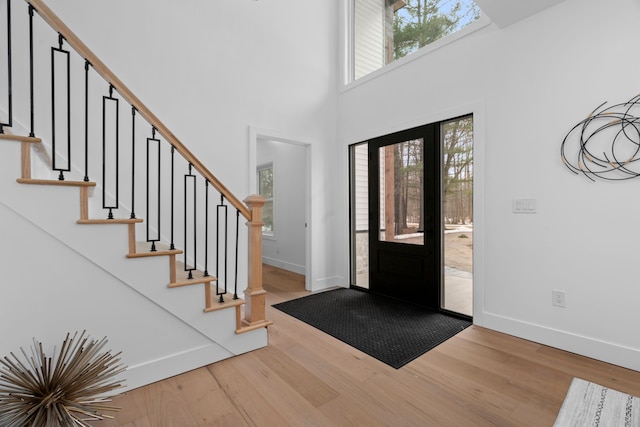 foyer entrance featuring stairs, a high ceiling, wood finished floors, and baseboards