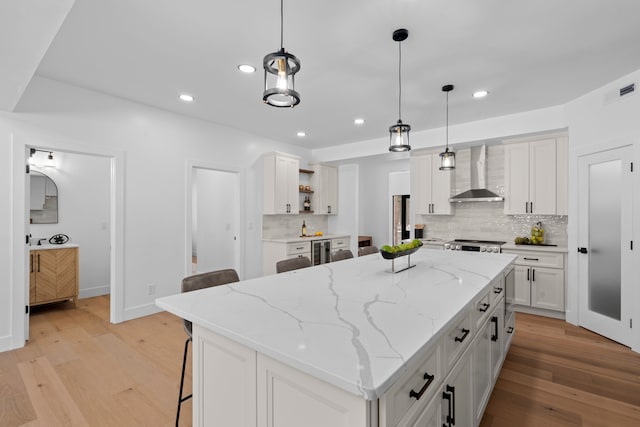 kitchen with visible vents, white cabinets, wall chimney range hood, light wood-type flooring, and open shelves