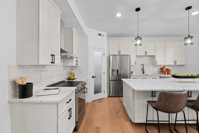 kitchen with appliances with stainless steel finishes, a breakfast bar, and white cabinetry