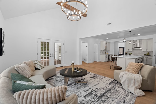 living area with french doors, visible vents, baseboards, and light wood finished floors