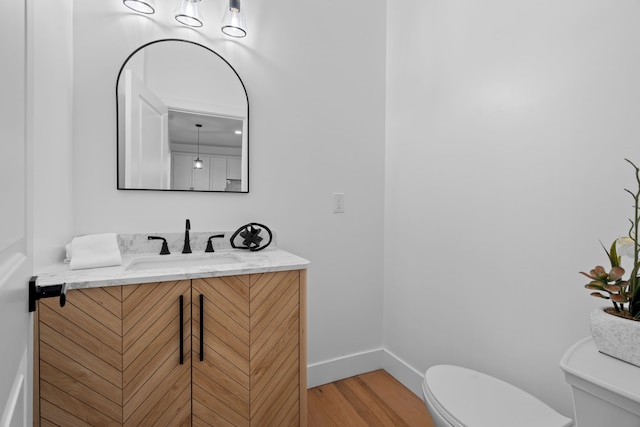 bathroom with baseboards, vanity, toilet, and wood finished floors