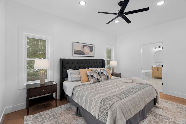 bedroom featuring connected bathroom, baseboards, wood finished floors, and recessed lighting