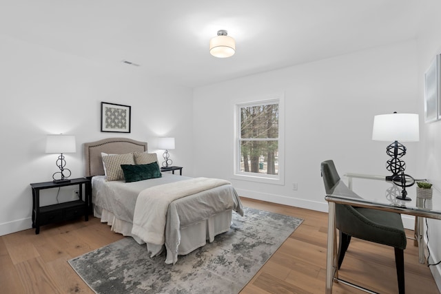 bedroom with visible vents, baseboards, and wood finished floors