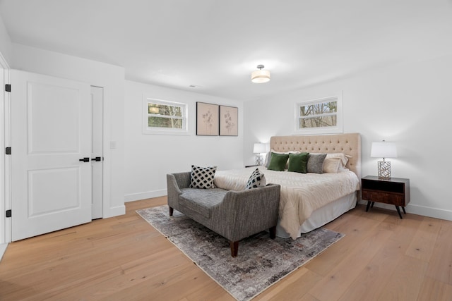 bedroom featuring multiple windows, light wood-style flooring, and baseboards