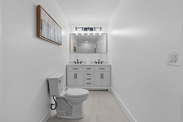 bathroom featuring double vanity, a sink, toilet, and baseboards