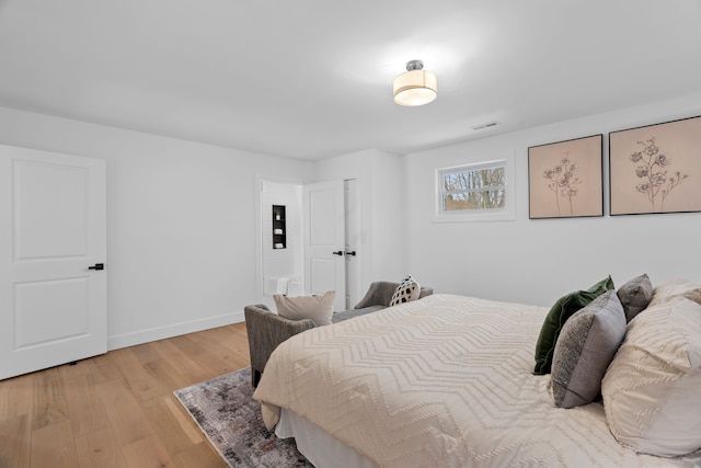 bedroom featuring baseboards, visible vents, and light wood finished floors