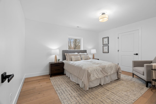 bedroom with baseboards, visible vents, and light wood-style floors