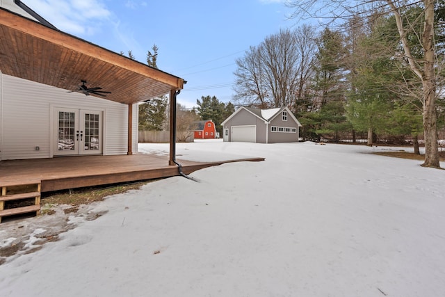 view of yard with french doors, a detached garage, a ceiling fan, a deck, and an outdoor structure