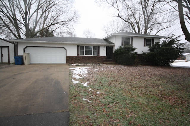 tri-level home with a garage, concrete driveway, brick siding, and stucco siding