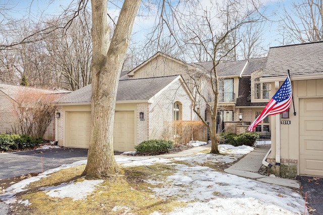 view of front of home featuring a shingled roof, brick siding, a garage, and aphalt driveway