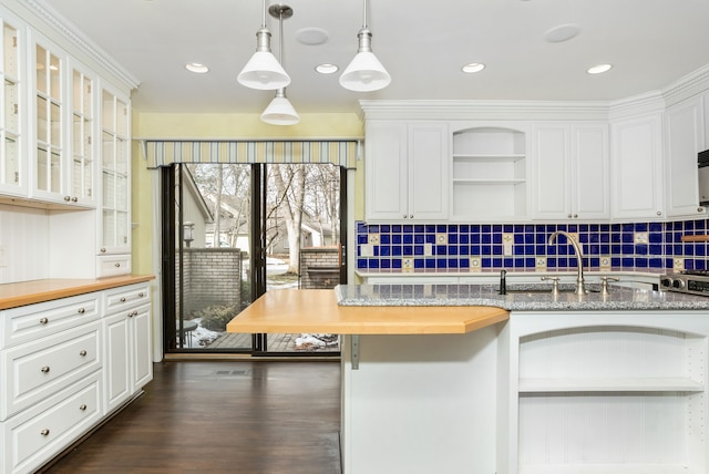 kitchen with a sink, white cabinetry, hanging light fixtures, open shelves, and glass insert cabinets