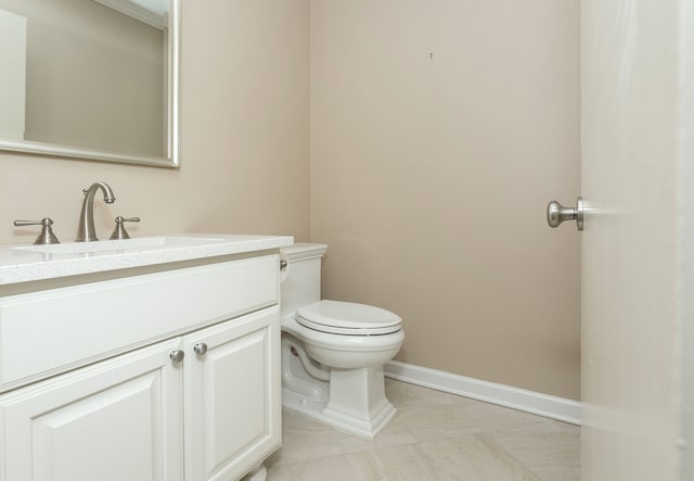 half bathroom featuring baseboards, vanity, and toilet