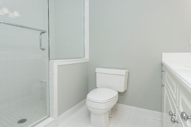 full bathroom with toilet, vanity, a tile shower, baseboards, and tile patterned flooring