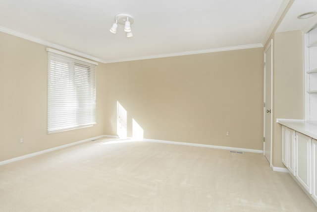 empty room with baseboards, crown molding, and light carpet