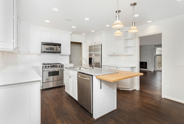 kitchen featuring a sink, decorative backsplash, a kitchen island with sink, white cabinets, and appliances with stainless steel finishes