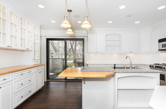 kitchen featuring stainless steel gas stove, backsplash, a sink, and white cabinetry