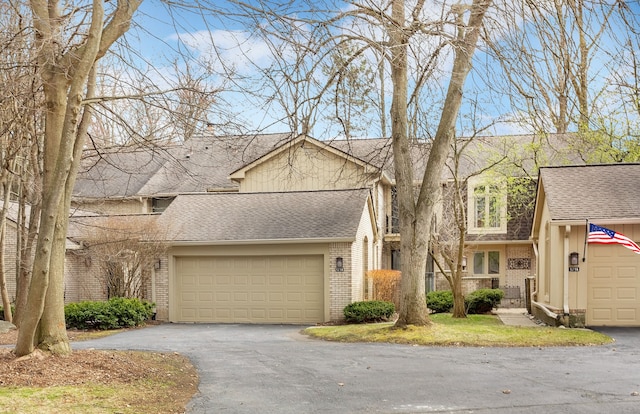 view of front of house with an attached garage, brick siding, aphalt driveway, and a shingled roof