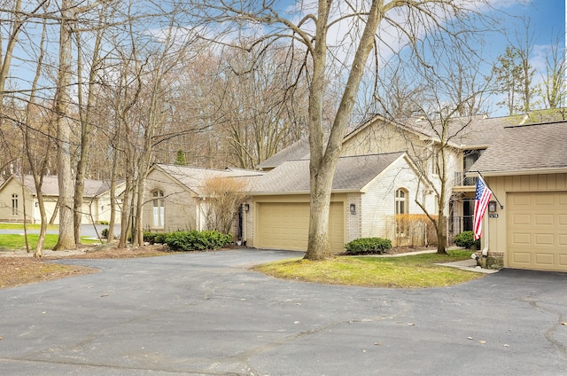 view of front of home with brick siding, an attached garage, driveway, and roof with shingles