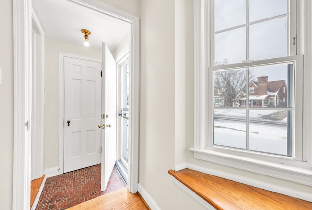 doorway with brick floor and baseboards